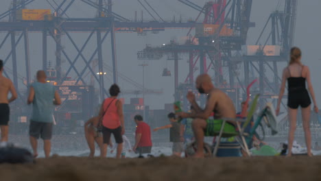 Hafen-Mit-Containerkränen-Und-überfülltem-Strand-In-Valencia,-Spanien