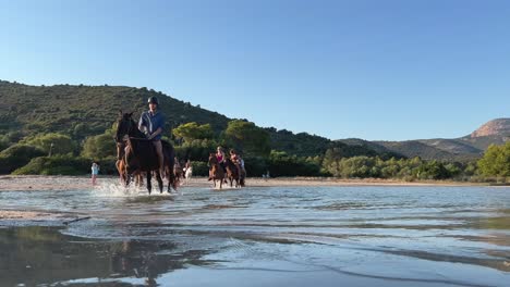 Touristen-Reiten-In-Der-Sommersaison-Auf-Pferden-Im-Meerwasser