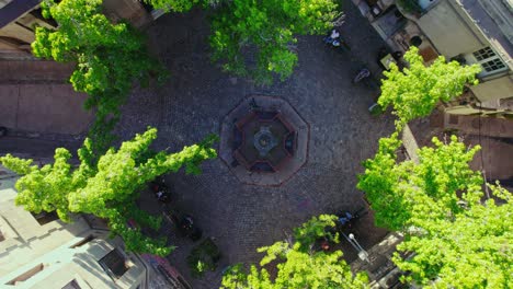Spiral-overhead-view-of-the-fountain-in-the-freedom-of-the-press-square-cobblestone-streets-of-the-Concha-y-Toro-neighborhood,-Santiago-Chile