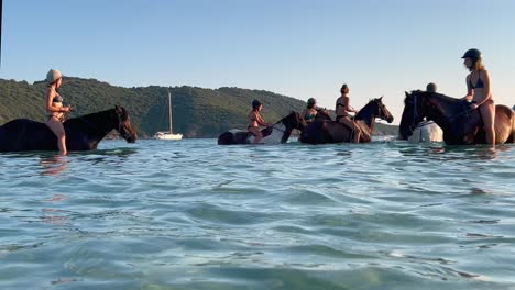 People-enjoy-riding-horse-in-sea-water-in-summer-season-with-boats-in-background