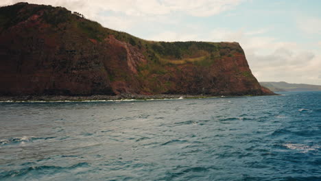 Slow-motion-view-of-high-cliffs-rocky-coastline-from-the-ocean