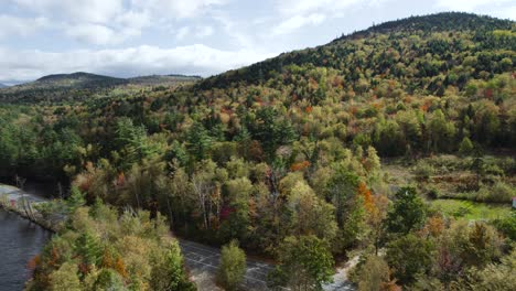 Aerial-reveal-of-highway-near-sunny-fall-forest-on-hillside-and-lake