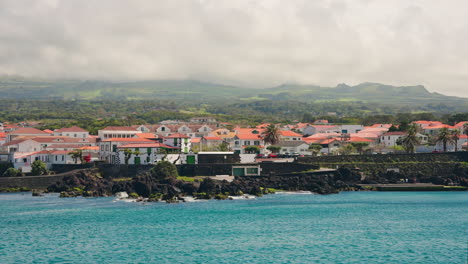 Small-local-town-with-orange-rooftops-located-on-the-rocky-coastline-of-the-Azores-Islands,-Atlantic-ocean,-Portugal