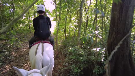 Adult-male-practicing-horseback-riding,-wearing-protection-gear-and-a-backpack,-in-the-rainforests-of-Costa-Rica