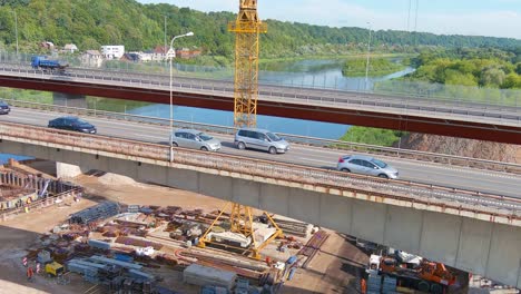 Semirremolques-Y-Automóviles-Cruzando-El-Puente-Cerca-Del-Sitio-De-Construcción,-Vista-Aérea-De-Drones