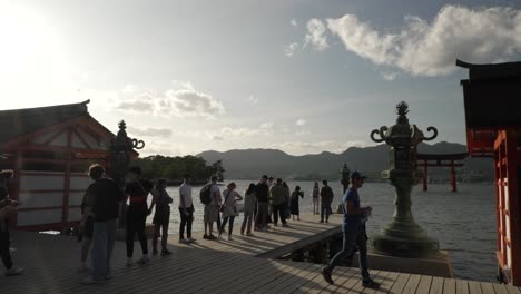 Touristen-Stehen-Schlange,-Um-Während-Der-Goldenen-Stunde-Ein-Foto-Von-Itsukushima-Jinja-Otorii-Zu-Machen,-Das-Im-Wasser-Schwimmt