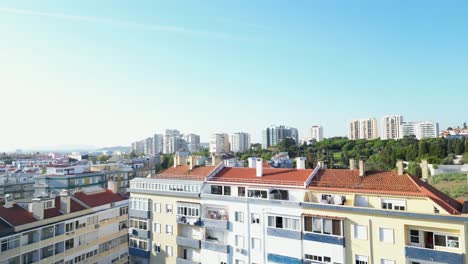Bright-Lisbon-neighborhood-with-terracotta-roofs-under-clear-skies-and-high-rise-buildings,-Lisbon,-Portugal