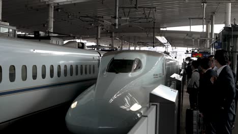 Shinkansen-Hochgeschwindigkeitszug-Der-N700-Serie-Kommt-Am-Bahnsteig-Des-Hiroshima-Bahnsteigs-An,-Während-Der-Pendler-Hinter-Dem-Sicherheitsgeländer-Wartet