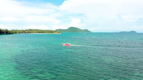 Drone-shot-strafing-from-right-to-the-left-revealing-the-rest-of-Rawai-beachfront-with-its-sandy-beach,-crystal-clear-waters,-and-boats-anchored-along-the-coastline,-located-in-Phuket,-Thailand