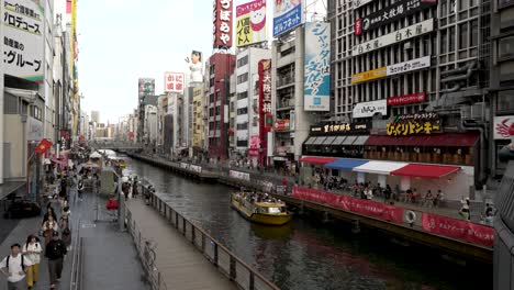 View-Of-Dotonbori-Canal-With-Tombori-River-Cruise-Boat-Sailing-Along-On-Overcast-Day-In-Osaka