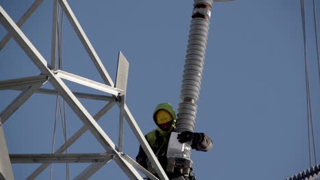 A-worker-installs-a-condenser-on-a-pole-for-a-high-voltage-power-line