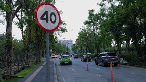 Señal-De-Carretera-De-40-Km,-Un-Automóvil-Verde-Se-Detiene-Por-Un-Momento-Con-Las-Luces-De-Emergencia-Encendidas-Mientras-Otros-A-La-Derecha-Continúan,-Chaeng-Wathana,-Bangkok,-Tailandia