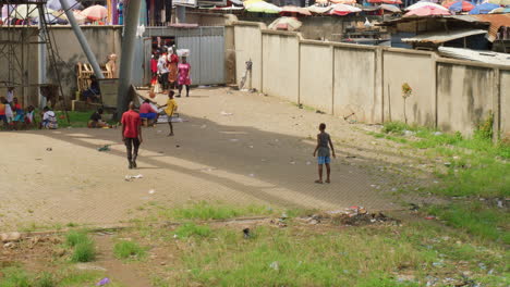 Schwarzafrikanische-Kinder-Spielen-Mit-Ballfußball-Auf-Der-Straße-Eines-Ländlichen,-Abgelegenen-Dorfes