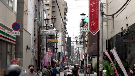 Calle-Lateral-En-La-Zona-De-Dotonbori-En-Osaka-Con-Gente-Y-Tráfico-Ligero-En-La-Carretera