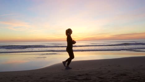 woman-running-along-the-seashore-with-beautiful-sunrise-light-in-the-sky