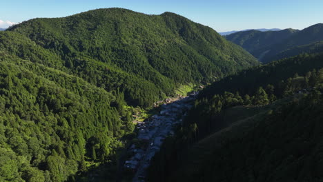 Aerial-tracking-shot-overlooking-the-Kurama-mountain-town,-in-sunny-Japan