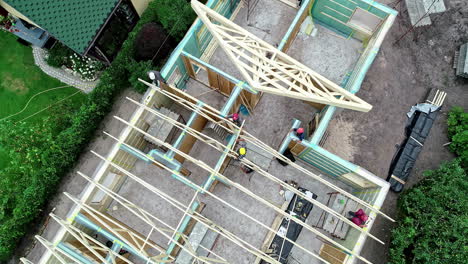 Aerial-footage-of-under-construction-house-with-a-wooden-frame-with-active-workers-engaged-in-building