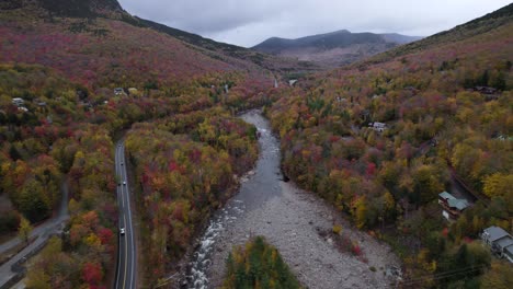 Cinematic-view-over-Kancamagus-highway-near-river-and-colorful-fall-forest