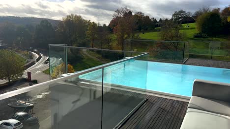 Pov-walk-on-top-of-hotel,-approaching-Swimming-pool-outdoors-during-sunny-day-in-Germany,-Sauerland