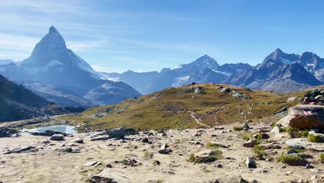 Mountain-Freedom:-Matterhorn-Mountain-Landscape-Near-Rotenboden-and-Gornergart,-Switzerland,-Europe-|-Moving-Over-Hillside-Towards-Rock-Sculptures-Overlooking-Scenic-Lake,-Hiking