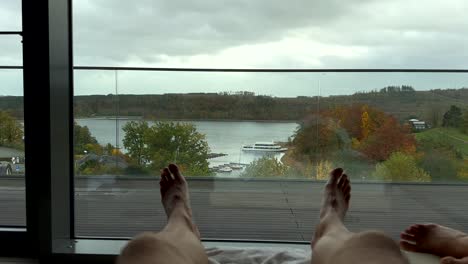 Pov-shot-of-male-person-relaxing-in-bed-at-spa-area-and-watching-lake-view-during-cloudy-day---static-wide-shot