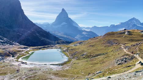 Mountain-Freedom:-Matterhorn-Mountain-Landscape-Near-Rotenboden-and-Gornergart,-Switzerland,-Europe-|-Moving-Down-Trail-As-Travel-Couple-Moves-Towards-Scenic-Lake,-Hiking