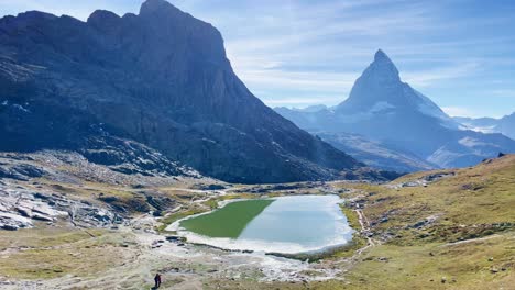 Mountain-Freedom:-Matterhorn-Mountain-Landscape-Near-Rotenboden-and-Gornergart,-Switzerland,-Europe-|-Shaky-Movement-Down-Trail-Overlooking-Scenic-Lake-and-Travel-Couple,-Hiking