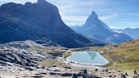 Mountain-Freedom:-Matterhorn-Mountain-Landscape-Near-Rotenboden-and-Gornergart,-Switzerland,-Europe-|-Moving-Near-Rock-Sculptures-on-Hillside-Edge-Overlooking-Scenic-Lake,-Hiking
