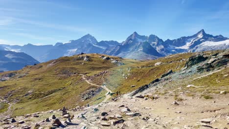 Mountain-Freedom:-Matterhorn-Mountain-Landscape-Near-Rotenboden-and-Gornergart,-Switzerland,-Europe-|-Shaky-Movement-Over-Rough-Landscape-Near-Rock-Sculptures-as-Travel-Couple-Explores-Ahead,-Hiking