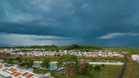 Aerial-View-Of-Dramatic-Cloudscapes-With-Rainbow-Over-Housing-Complex-Near-Jamundi-Colombia