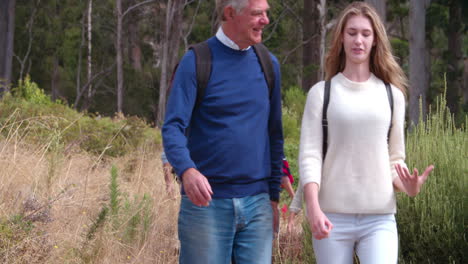 Grandfather-and-granddaughter-walking-together-near-a-forest