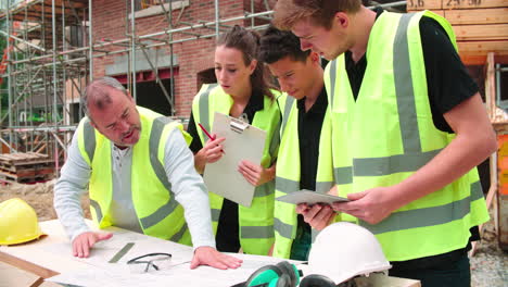 Builder-On-Building-Site-Discussing-Work-With-Apprentices