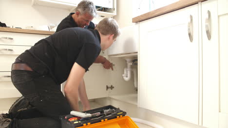 Plumber-teaching-apprentice-to-fix-kitchen-sink