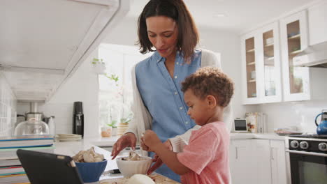 Millennial-mother-and-toddler-son-preparing-food-together-in-the-kitchen,-side-view,-close-up