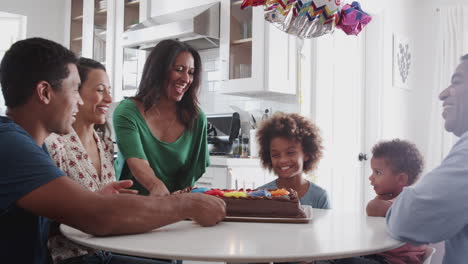 Multi-generation-family-sitting-at-a-table-in-the-kitchen-celebrating-girl’s-birthday,-close-up