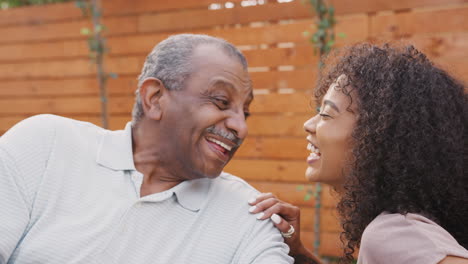 Senior-black-man-and-his-adult-granddaughter-laughing-outdoors,-close-up