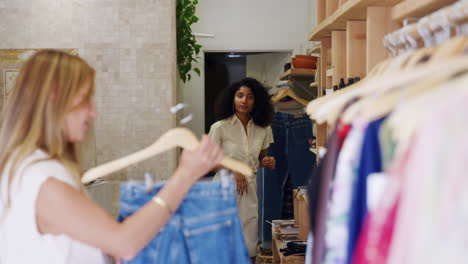 Mujer-Comprando-Jeans-En-Una-Tienda-De-Moda-Pidiendo-Ayuda-Al-Asistente-De-Ventas