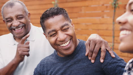 Three-generations-of-black-family-men-laughing-together-outdoors,-close-up