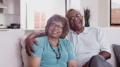 Senior-black-couple-sit-talking-and-smiling-to-camera-at-home,-close-up