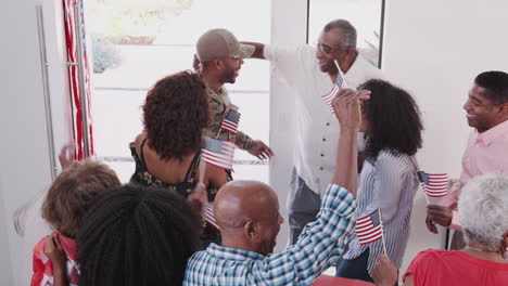 Young-black-soldier-returning-to-a-surprise-family-welcome-home-party,-elevated-view
