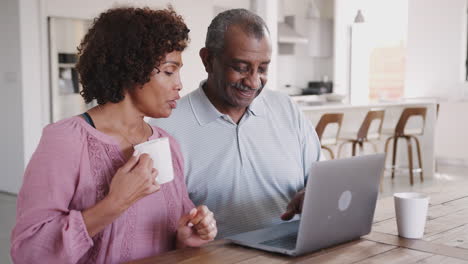 Senior-black-man-and-his-middle-aged-daughter-using-a-laptop-together-at-home,-close-up