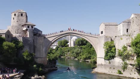 Stari-Most-Arqueándose-Sobre-Las-Aguas-Azules-Del-Río-Neretva,-Mostar-Bosnia
