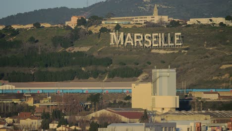 Vista-De-Marsella-Con-El-Nombre-De-La-Ciudad-En-Colinas-Verdes-Francia