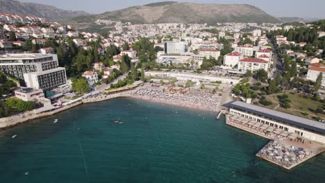 Uvala-Lapad-beach-packed-with-visitors-sunbathing-in-Dubrovnik-Croatia,-aerial