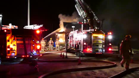 fireman-climbing-down-the-back-of-a-ladder-pump-truck-during-a-large-house-fire-emergency