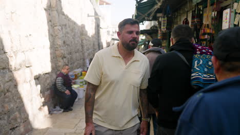 Fotógrafo-Sosteniendo-Una-Cámara-Caminando-Por-La-Concurrida-Calle-De-Jerusalén,-Israel
