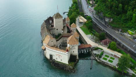 drone-camera-is-moving-from-behind-the-castle,-and-behind-the-castle-is-the-name-'musee-fort-de-chillon'-HOLLYWOOD-shot-in-Chillon-castle-Switzerland