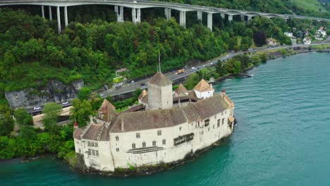 Drone-camera-is-flying-over-Chillon-castle,-and-many-tourists-come-here-for-vacation