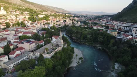 River-Neretva-in-balkan-city-Mostar,-aerial-orbit-during-sunset,-ancient-skyline