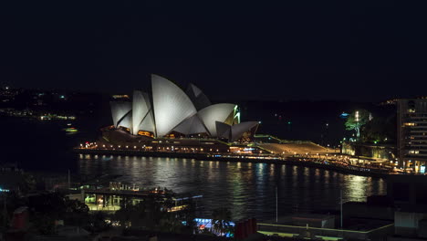 Boat-traffic-around-Sydney-Opera-House,-illuminated-at-night,-Timelapse